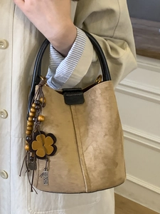 Vintage frosted suede bucket bag in beige with black leather handles and boho charms