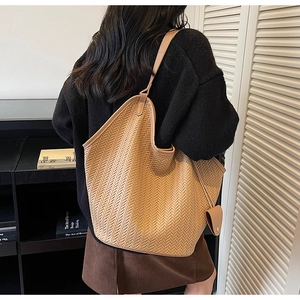 Détail d'un sac hobo tressé marron clair avec texture en V et pochette latérale assortie