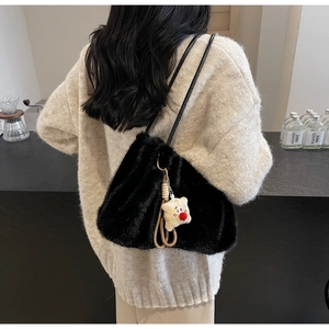 Dettaglio della borsa tote in peluche nero con spalline sottili e ciondolo a forma di orsetto