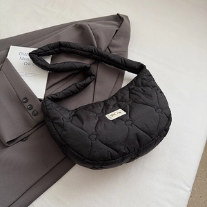 Makroaufnahme einer schwarzen Stepptasche mit Herzmuster, weichem Gurt und Webetikett