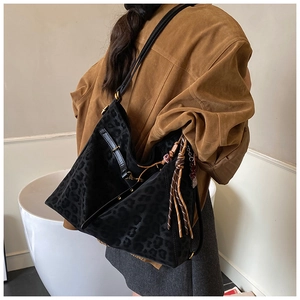 Detail of black leopard print tote bag with fringe charm and matte suede texture