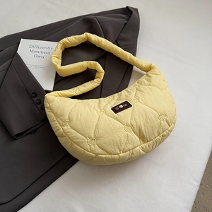 Detail der gelben gesteppten Herzmuster-Tasche auf grauem Blazer mit Buch-Dekoration