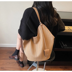 Détail d'un grand cabas tressé couleur caramel vu de dos à 45 degrés porté par un mannequin