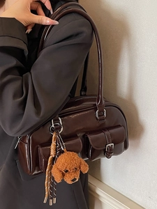 Deep brown glossy shoulder bag with pockets and cute plush dog charm shown on model