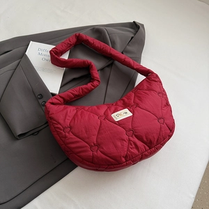 Detail der roten gesteppten Tasche mit Herzmuster, breitem Schultergurt und Webetikett