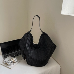 Détail du sac hobo tissé noir avec fine bandoulière et petit accessoire assorti