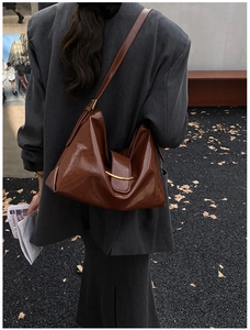 Détail du sac cabas brillant marron foncé avec anneau doré et texture en cuir drapé