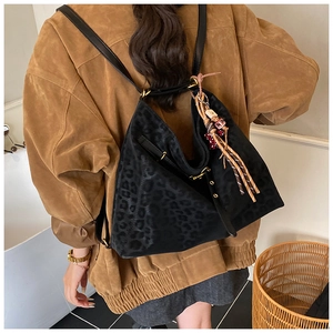 Detail of leopard print backpack with ethnic tassels and metallic gold buckle ornaments