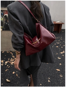 Sac fourre-tout en cuir brillant bordeaux avec boucle dorée porté à l'épaule en automne