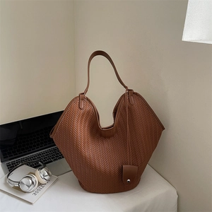 Gros plan d'un sac cabas tissé marron avec texture à chevrons et pochette assortie