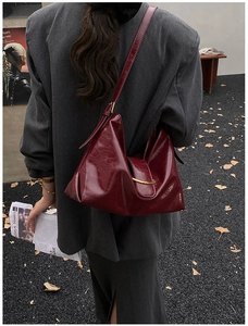 Détail du sac hobo en cuir verni bordeaux avec une boucle en métal doré élégante