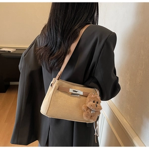 Detail of light brown matte shoulder bag with silver twist lock and cute dog charm