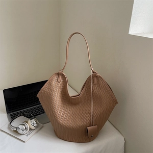 Détail du sac cabas tressé marron avec fine bandoulière et petite pochette boutonnée assortie
