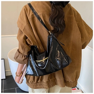 Gros plan sur le sac sous le bras noir brillant avec boucle en métal doré en forme de lune