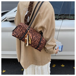 Close-up of leopard print barrel bag featuring leather straps and colorful beaded tassels