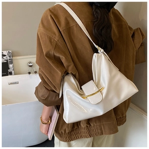 Détail du sac à bandoulière en cuir verni blanc avec boucle dorée sur veste en daim marron