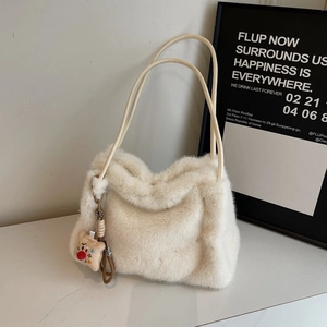 Dettaglio della borsa in peluche bianco crema con consistenza morbida e ciondolo orsetto