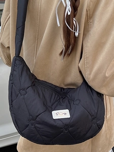 Schwarze Halbmond-Schultertasche mit Herzsteppung und Logo-Aufnäher im Herbst-Stil