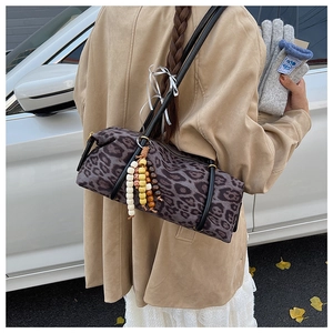 Detail view of leopard print cylindrical bag with colorful beaded tassels and black strap