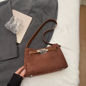Detail of brown suede crossbody bag with horizontal leather strap and silver metal buckle