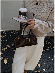 Detail showing high-shine leather texture and gold buckle of vintage tote bag
