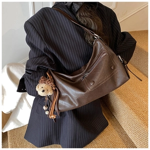 Detailansicht der dunkelbraunen Vintage-Leder-Umhängetasche mit Teddybär-Anhänger am Model