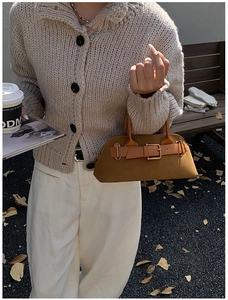 Close-up of brown suede handbag with decorative buckle detail in autumn setting