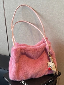 Borsa a spalla in peluche rosa arricciata con un simpatico ciondolo su sfondo morbido