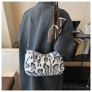 Detail of faux fur leopard print bag with silver chain strap worn with wool coat