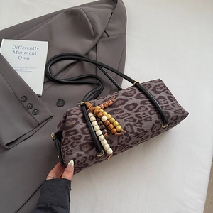 Detail view of leopard print barrel bag with beaded charm on gray suit background