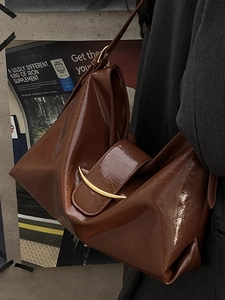 Sac cabas en cuir verni marron avec boucle en métal doré dans un décor urbain chic