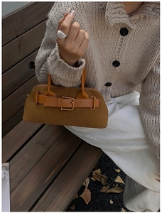 Close-up of retro brown suede tote bag with metal buckle detail on a wooden bench
