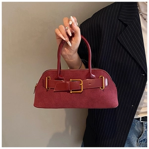 Close-up of a burgundy suede Boston bag featuring an elegant metal buckle and top handle