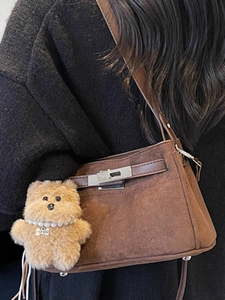 Brown frosted suede crossbody bag with metal lock and plush bear pendant detail