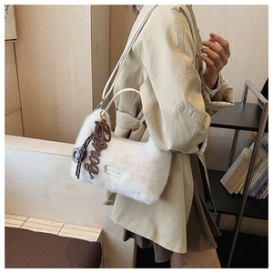 Detail of white plush shoulder bag featuring a fuzzy texture and stylish letter pendant