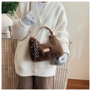 Detail of soft brown faux fur shoulder bag with metal logo and decorative keychain