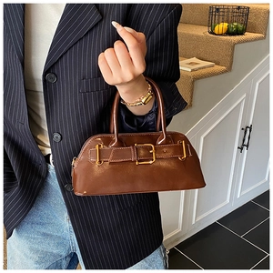 Detail of vintage brown tote bag with glossy finish and gold buckle on navy blazer