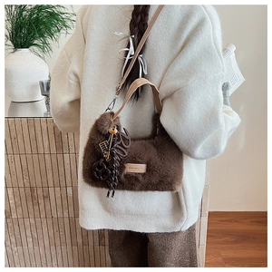 Plush brown crossbody bag with faux fur texture and leather strap shown on a model