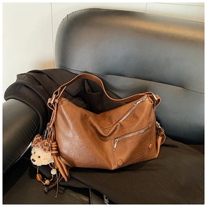 Detail der braunen Vintage-Hobo-Tasche mit Silberzippern und Plüschbär-Anhänger