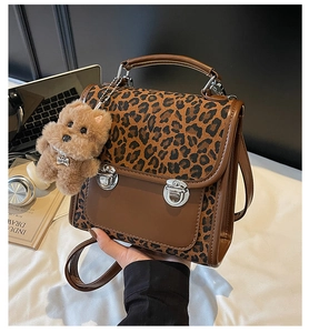 Detail of leopard print handbag with plush dog charm and silver metal locks