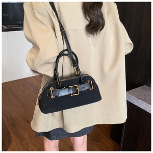 Detailed close-up of matte black leather handbag with elegant gold buckle and hardware