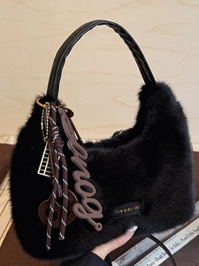 Chic black faux fur crescent hobo bag with trendy charms on warm wooden background