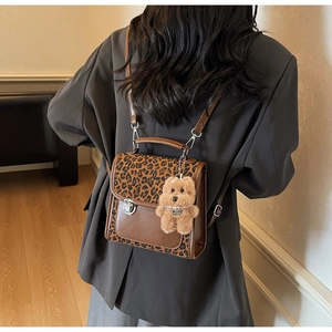Detail of vintage leopard print backpack with silver buckle and plush puppy charm