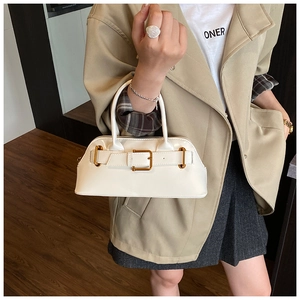 Detail of white glossy tote bag with gold metal buckle held by model in trench coat