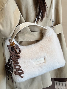 White faux fur handbag with 'Love' patch and woven charm shown on a beige trench coat