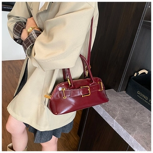 Detailed view of dark red vintage handbag with glossy leather and golden hardware