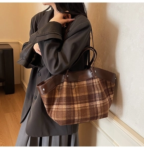 Close-up of vintage plaid tote bag featuring brown wool fabric and leather handle detail