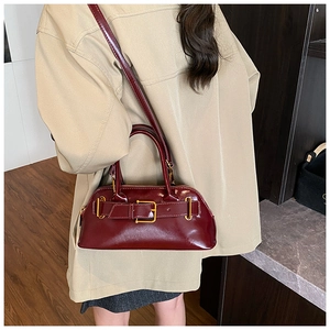 Detail view of the deep wine red glossy leather handbag with elegant gold metal buckle