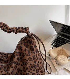 Detail of leopard print tote bag with ruffled strap and silver buckle on a stylish desk