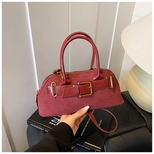 Detail of burgundy vintage handbag showing suede and glossy leather textures with buckled straps